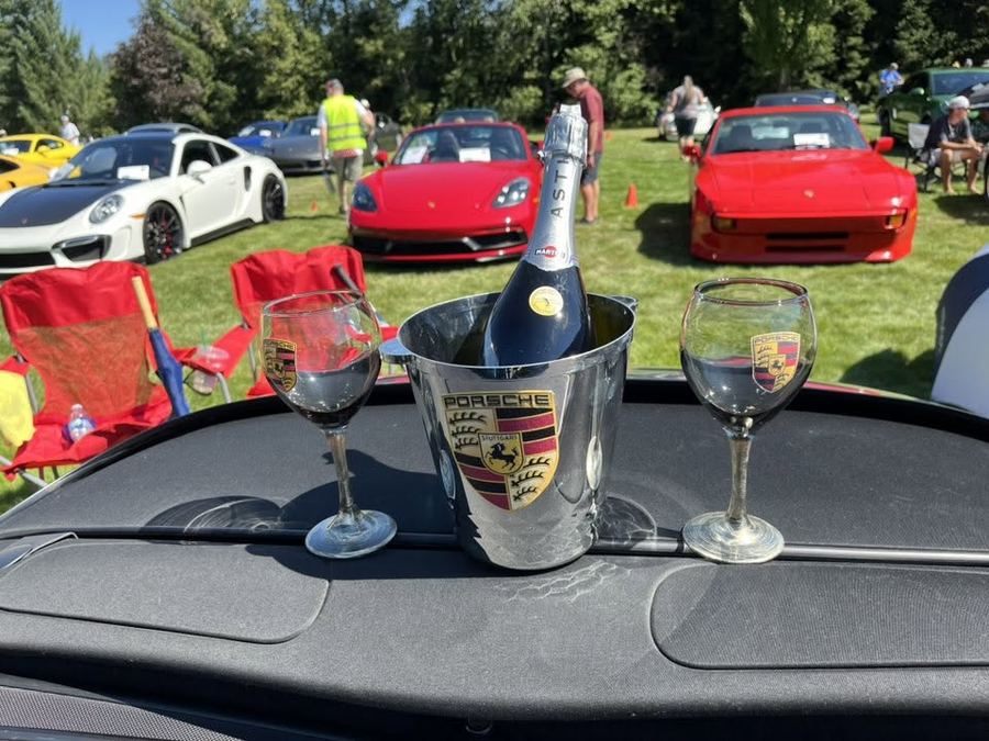 Champagne toast in a Porsche crest ice bucket with cars in the background