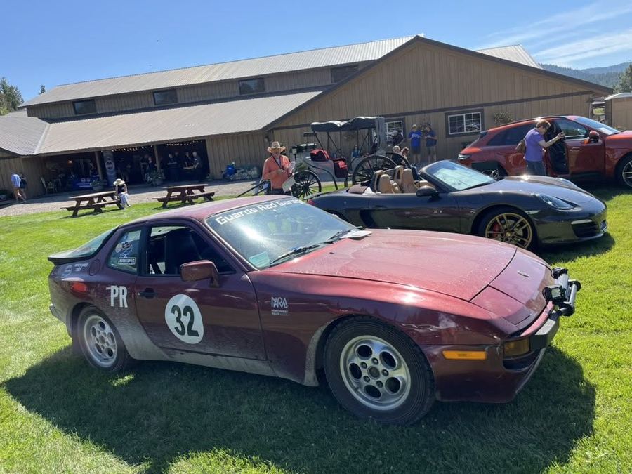 Maroon vintage race car with number 32 parked near the barn